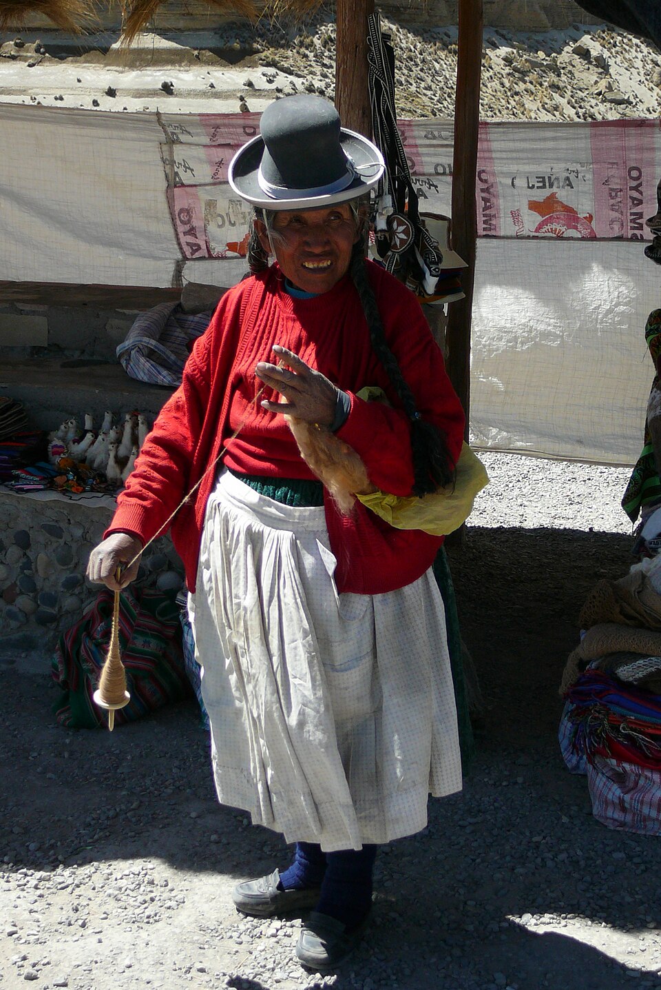 Mujer andina hilando lana